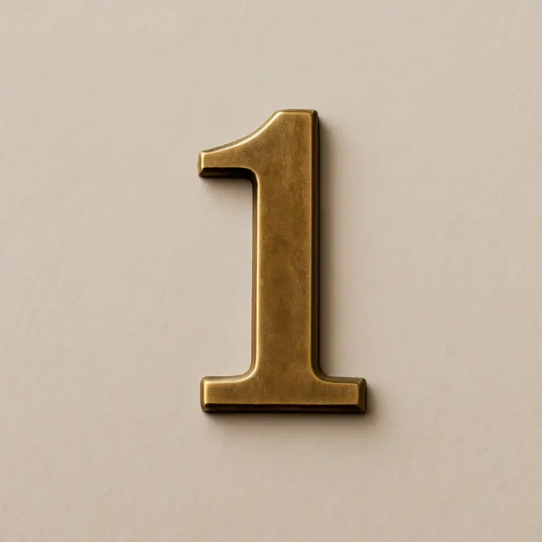 A brass number "1" lying slightly tilted on a textured dark surface, illuminated by soft ambient light.
