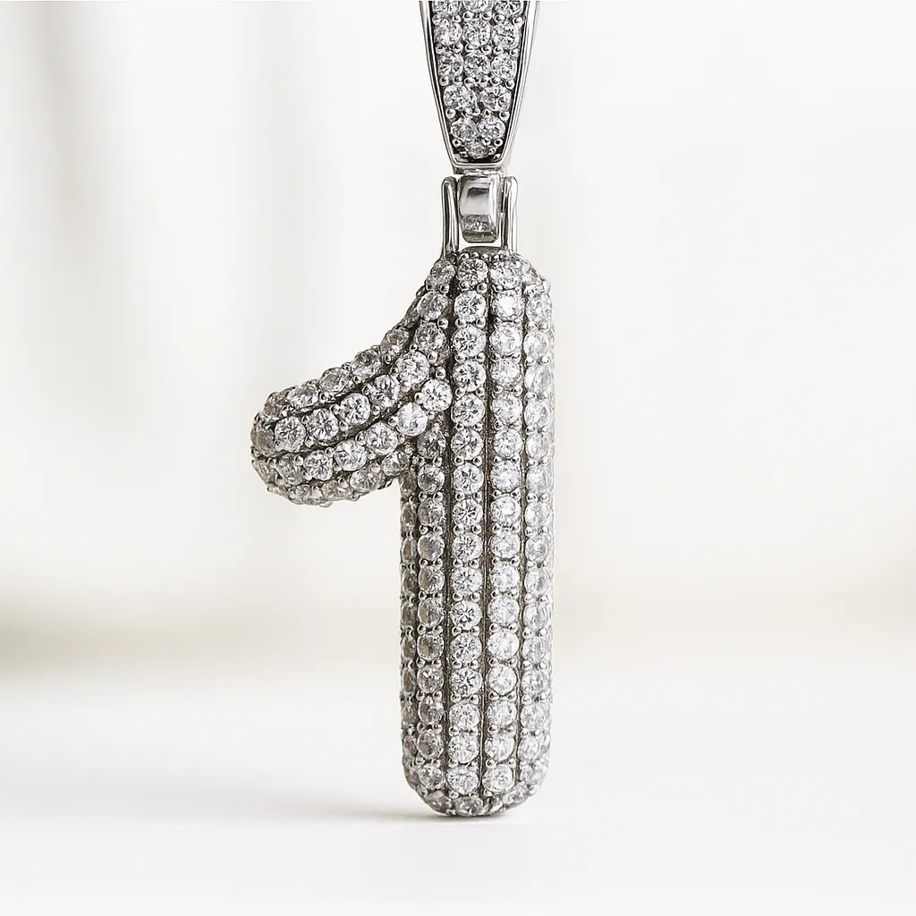 A photograph showcases a number "1" pendant encrusted with rows of round diamonds, set in shiny white metal, against a soft white background.